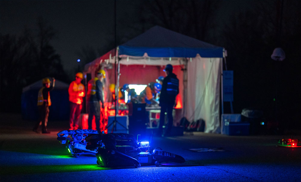 Uncrewed ground vehicles and teams prepare to take on the night course, DARPA Triage Challenge Workshop 2.